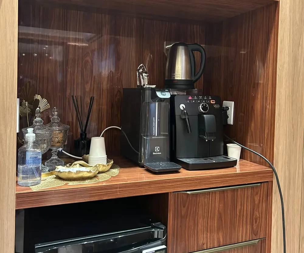 Copa da unidade com máquina de café, filtro de água e chaleira em móvel de madeira